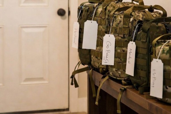 A packed evacuation bag with its contents laid out on a bed