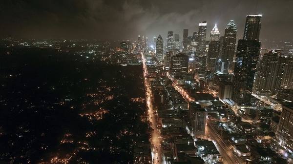 Aerial view of major American city at night with half completely dark and half fully lit showing rolling blackout