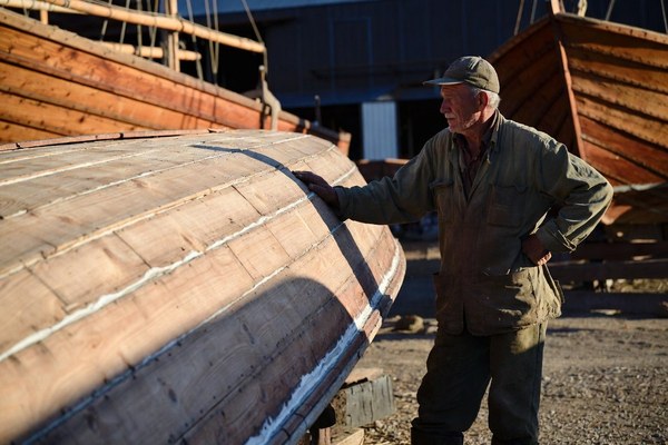 Hands fairing the curve of a wooden boat hull