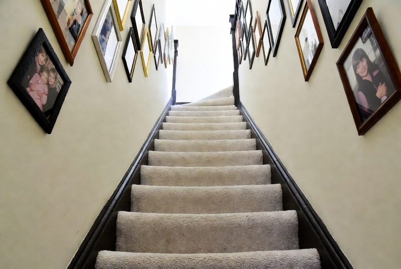 A carpeted staircase seen from the bottom, treads and risers all the same pale cream, with the edge of each step hard to make out